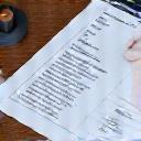Hand holding a pen over an application form, symbolizing preparation